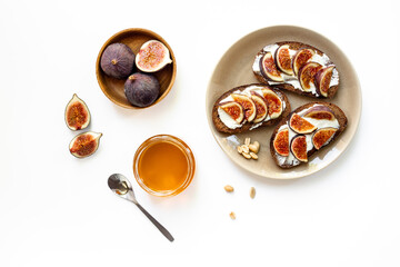 Figs and cheese toasts on the plate with jar of honey, top view