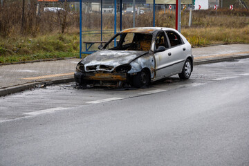 Fototapeta premium Burnt passenger car standing on the road. Vehicle with interior largely burned out.