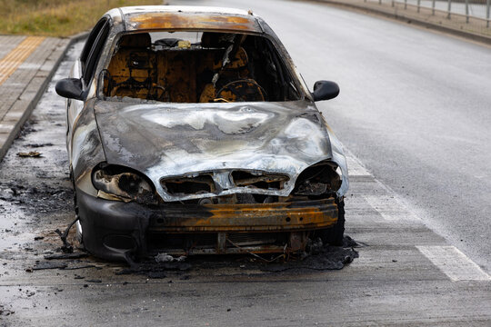 Burnt passenger car standing on the road. Vehicle with interior largely burned out.