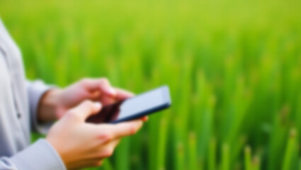 blurred photo concept of person holding smartphone near grass. Ideal for technology, communication, social media, lifestyle, nature, or outdoor activities related concepts.