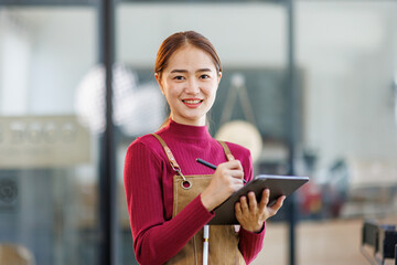 Startup successful small business owner sme beauty girl stand with tablet in coffee shop restaurant. Portrait of asian tan woman barista cafe owner. SME entrepreneur seller business concept
