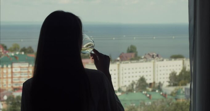 Woman drinking wine and looking at city view