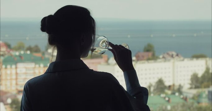 Woman drinking wine and looking at cityscape