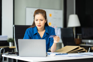 Fototapeta premium Serious woman cover her face after stressed with credit card debt sit at workplace desk in office use calculator calculates monthly expenses.
