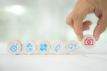 Hand chooses wooden toy stack with wellness medical care and healthy for family safety insurance plan or personnel sickness illness treatment concept.