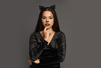 Attractive woman with cat makeup and ears on grey background