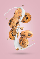 Chocolate chip cookies and splashing milk in air on pink background