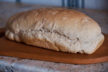Fresh rustic bread on a kitchen board. Side view. Selective focus