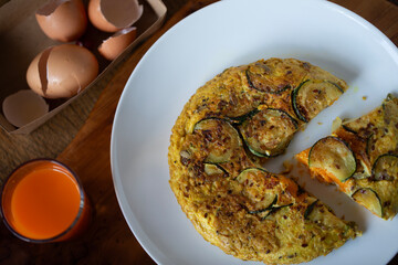 VEGETARIAN FRITTATA TOP VIEW ON WHITE PLATE EGG SHELLS  ORGANIC CARROT JUICE