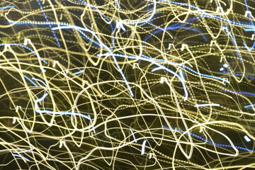 Abstract light painting with yellow and blue light trails captured in motion. 