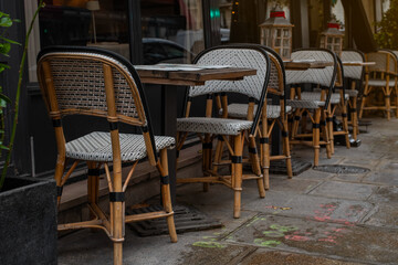 Quintessential Parisian café ambiance on a charming street in the 7th arrondissement. Elegant wicker chairs and wooden tables create an inviting scene perfect for dining, leisure, or urban lifestyle 