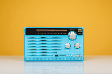 Close-up of old radio receiver light blue color on yellow background, front view.