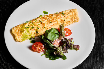 Savor a delicious omelette paired perfectly with a fresh salad and vibrant cherry tomatoes