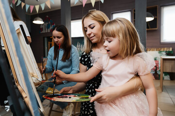 A mother and daughter create art together in a lively painting class