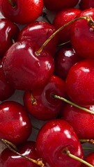 A bunch of juicy red cherries with shiny skins on a light background.