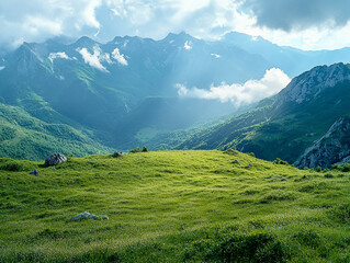 Fototapeta premium Green plateau with sweeping views of rugged mountain ranges and soft clouds
