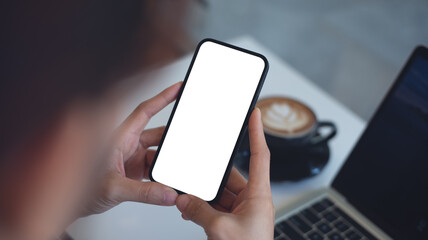 Cell phone white screen mockup, Woman hand holding mobile phone with blank screen while working at coffee shop. Business woman using smartphone, mockup for social media marketing
