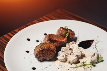 delicious pork fillet with mushrooms on wooden table in restaurant