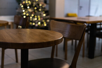 wooden tables in a cafe on the background of a bokeh garland of a Christmas tree