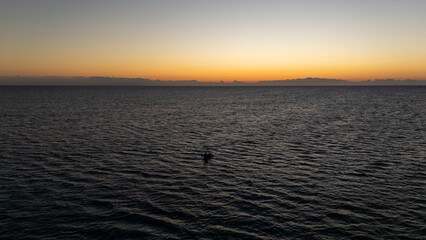 Obraz premium Drone aerial view deep in the sea during sunset with figherman