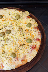 vista cenital en fondo negro de una pizza recien horneada con mucho queso