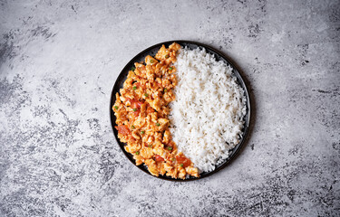 Tomato and eggs stir fry with rice in a plate