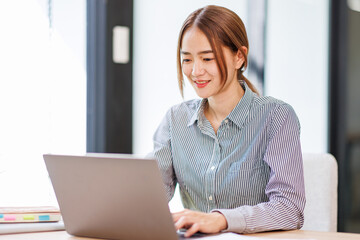 Asian businesswoman work on laptop computer at the office with calculator document on desk, doing planning analyzing the financial report, business plan investment, finance analysis concept.
