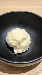 Mashed potatoes in a black cup on a wooden table
