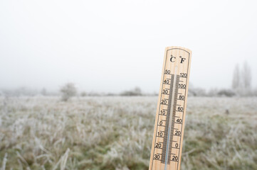 Thermometer with frost covered meadow, cold frosty weather forecast in winter, measure the...