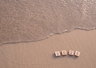 Wooden blocks with the number 2025 on the beach in the sunset time. New Year 2025 concept