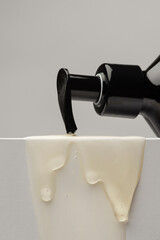 Dispenser with gel flowing down on white background
