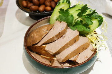 close up of Chinese Hong Kong Chaozhou style marinated goose liver foie gras slice with cucumber on the side in a blue bowl