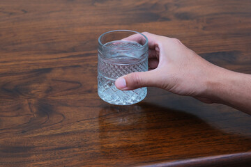 A person hand holding a glass of cold mineral water
