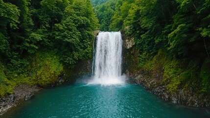A serene waterfall cascades into a turquoise pool, surrounded by lush greenery and rocky terrain, creating a tranquil natural scene.