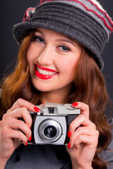 Vintage retro style portrait of beautiful smiling young woman holding an old film camera.
