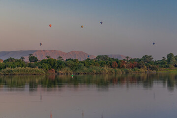 A mesmerizing view of vibrant hot air balloons floating at dawn over Luxor, Egypt