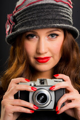 Vintage retro style portrait of beautiful smiling young woman holding an old film camera.