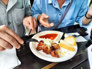 Dining experience featuring grilled food with sauce and bread in a casual setting during the day