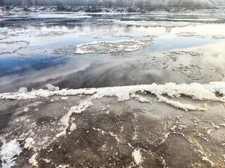 Drifting ice on a river highlights the transition of spring in a tranquil landscape © keleny