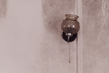 Unique vintage wall lamp hanging on a textured wall in a dimly lit room enhancing the cozy...