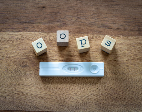 Positive Pregnancy Test with Wooden Letters Spelling Oops, A Concept of Unexpected Pregnancy