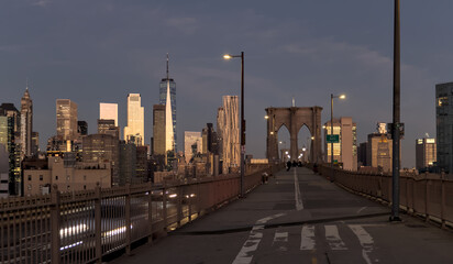 cars driving over the brooklyn bridge from manhattan new york city (long exposure light trails) traffic commute commuters traveling to work jobs (skyline background at dawn sunrise) dark night time