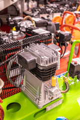 a silver air compressor pump mounted on a green base with a black cover over the top. other air...