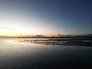 Silhouetted Figures Walking on Reflective Waters at Sunrise in the Philippines
