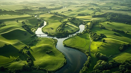 Aerial view of meandering river through green fields at sunrise.