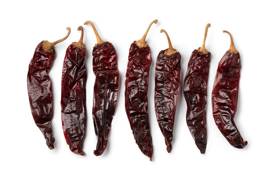 Dried Mexican guajillo chili peppers in a row isolated on white background close up