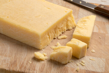 Extra mature english traditional cheddar cheese and pieces on a cutting board close up