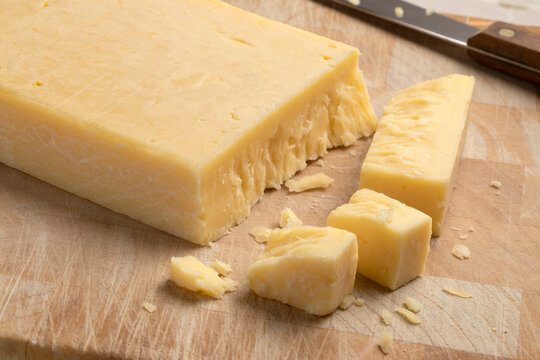 Extra mature english traditional cheddar cheese and pieces on a cutting board close up