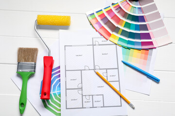 Designer's workplace with color palettes, floor plan and different supplies on white wooden table,...