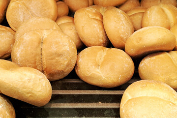 Fresh Kaiser rolls stacked on a store shelf. Group of classic bread rolls on display. Bakery section with a pile of golden brown buns. Perfect for sandwiches or breakfast. Crisp, freshly baked roll.
